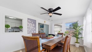 A dining area with a wooden table, chairs, a ceiling fan, and a potted plant.