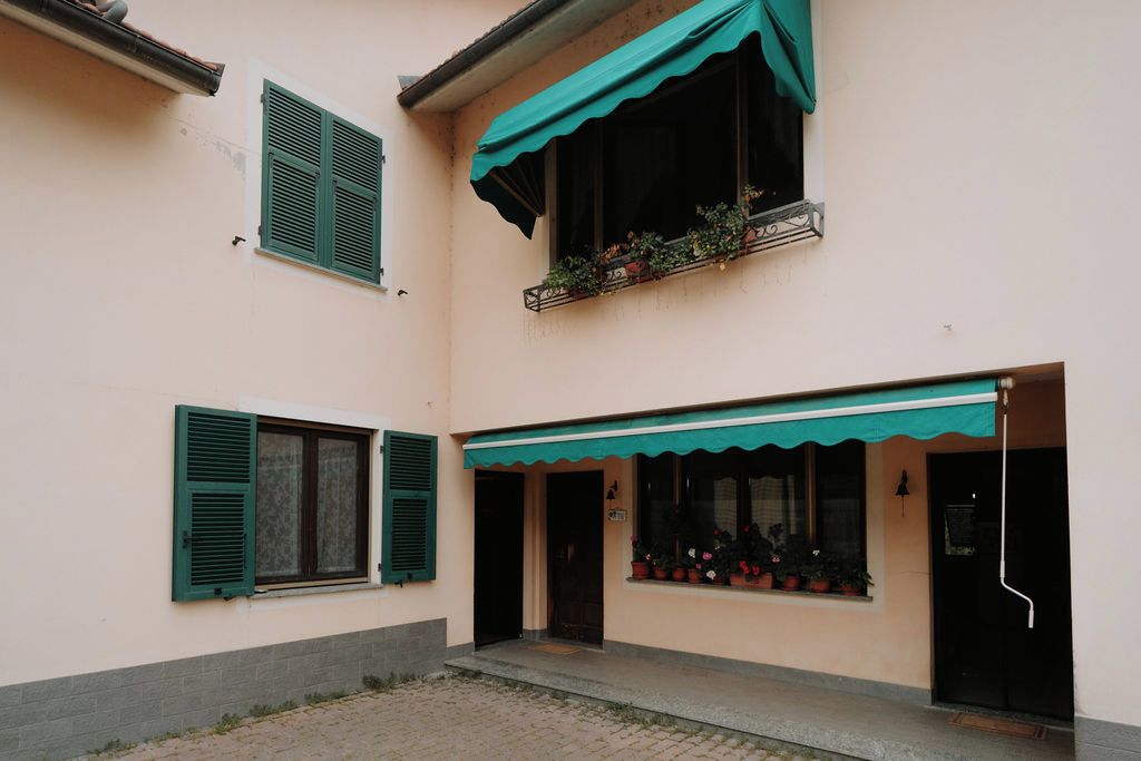 A building with a balcony, a door, and a window with shutters.
