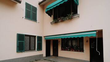 A building with a balcony, a door, and a window with shutters.