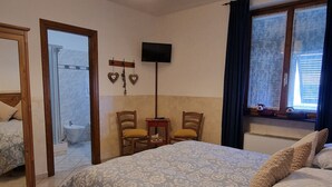 A hotel room with a bed, a desk, a chair, a television, and a window.