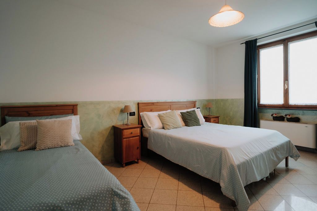 Une chambre avec deux lits, une table de chevet, une lampe et une fenêtre avec des rideaux.