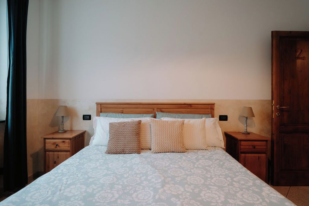 Ein Schlafzimmer mit einem Bett, zwei Nachttischen, einer Holztür und einer schlichten Wand.