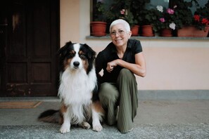 A person sitting next to a dog in front of a building with a door and potted plants. - Rural Lodging - Farmstay for 10 guests with 3 bedrooms and 3 bathrooms – Il Lavagè  (Rossiglione)