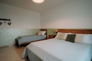 Un dormitorio con dos camas, un cabecero de madera, una mesita de noche y un estante en la pared con adornos con forma de corazón.