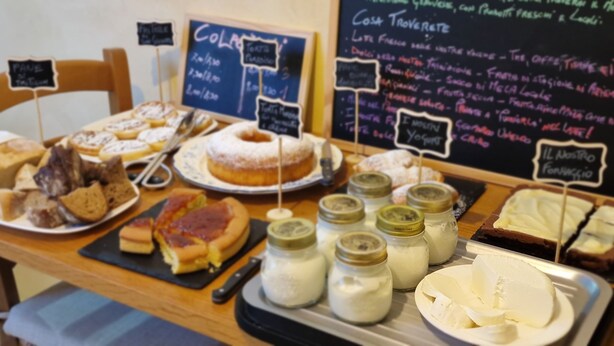 A variety of food items displayed on a table with a chalkboard menu in the background.