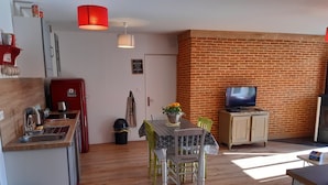 Un espacio habitable compacto con cocina, comedor y televisor.