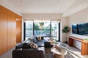 A modern living room with a sofa, coffee table, and TV. - Beautiful and Central Apartment (Puerto Vallarta)