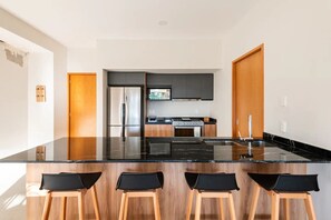 A modern kitchen with a large island, stainless steel appliances, and wooden accents. - Beautiful and Central Apartment (Puerto Vallarta)