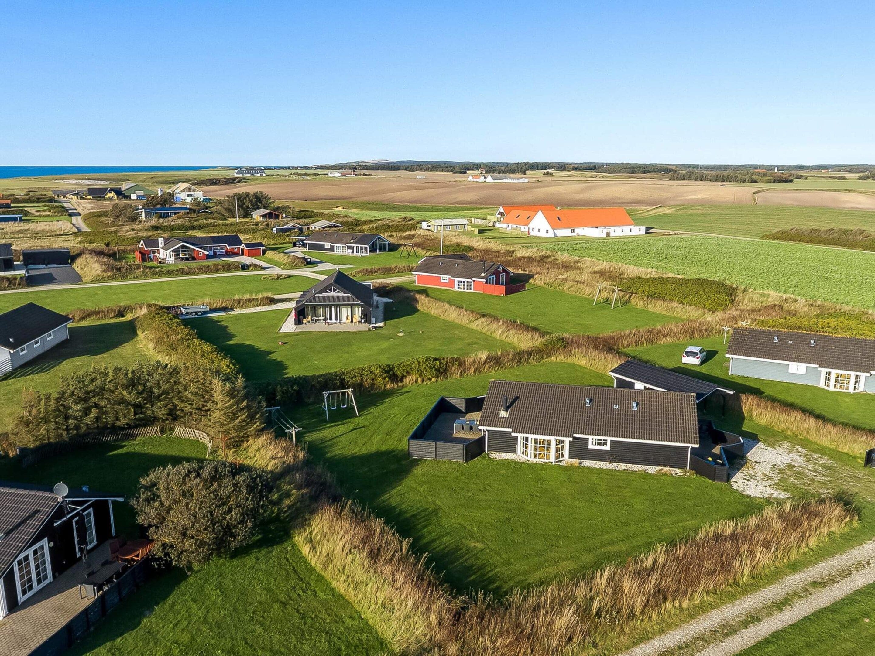 A residential area with houses, a playground, and a clear view of the sea.