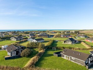 Eine Wohngegend an der Küste mit Häusern, grünen Feldern und blauem Himmel.