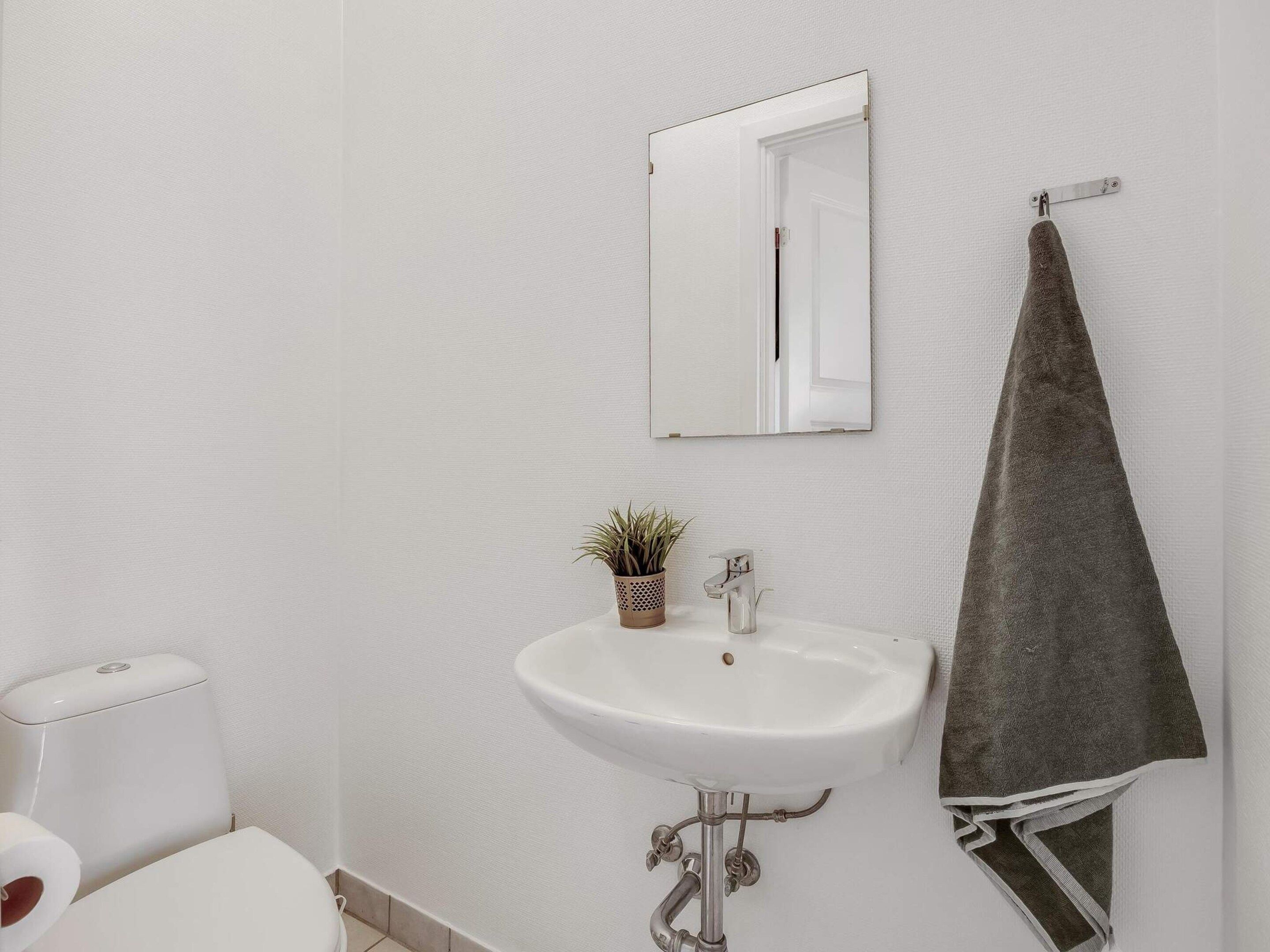 A bathroom with a white sink, a mirror, a towel hanging on a rack, and a toilet.