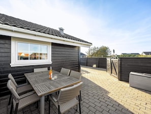 Eine Terrassenfläche mit Tisch und Stühlen, einer Flasche und einem Fenster mit Blick auf eine Wohngegend.