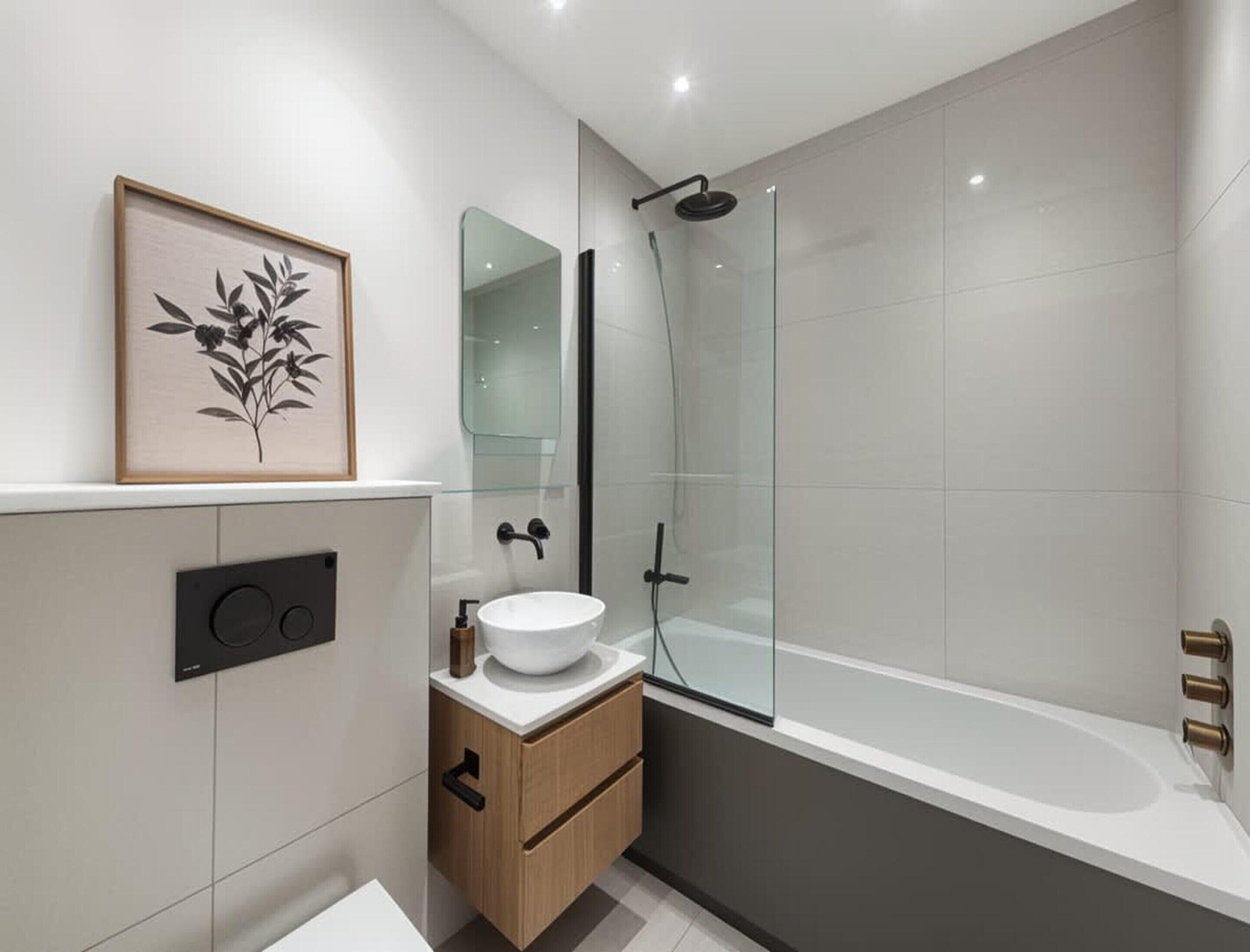 A modern bathroom with a glass shower enclosure, a white sink, and a framed botanical print on the wall.