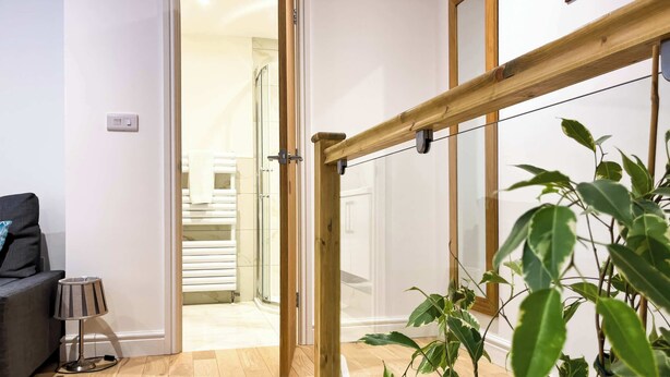 Una habitación con una escalera de madera, una planta en maceta, un sofá y un tambor.