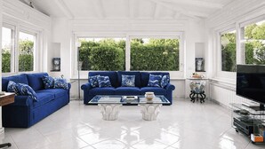 Una habitación amplia con un sofá azul, una mesita de centro de vidrio y una televisión.