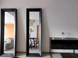 Ein modernes Zimmer mit einem großen Spiegel, einer dunklen Konsolentisch und einem Essbereich mit Stühlen und Tisch.
