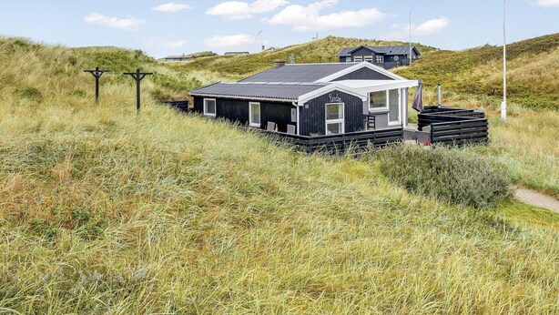 A coastal building with a dark exterior, a sloped roof, and a small porch area. - 4 Star Holiday Home in Lokken (Lokken)