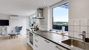 A modern kitchen with a large window, white cabinetry, and a built-in oven. - 4 Star Holiday Home in Lokken (Lokken)