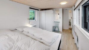 A bedroom with a bed, a window, a chair, and a wardrobe. - 4 Star Holiday Home in Lokken (Lokken)