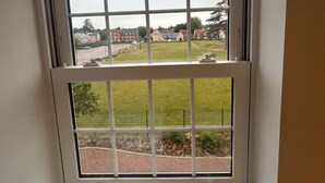 A window with a view of a grassy area and buildings in the distance. - Brampton Park (Brampton)