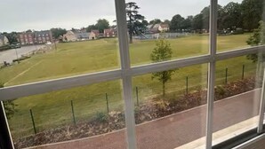 A view through a window with a clear sky, a grassy field, and a brick pathway. - Brampton Park (Brampton)