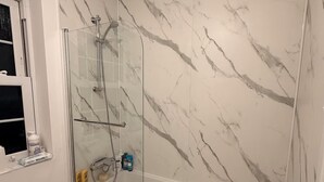 A bathroom with a glass-enclosed shower, marble walls, a bathtub, and a window. - Brampton Park (Brampton)