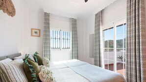 A bedroom with a bed, curtains, a window, and a view of the outdoors. - Holiday Home 'Vista Montana' with Lake Views, Wi-Fi, and Air Conditioning (Los Romanes)