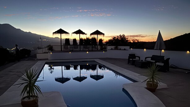 A swimming pool with a curved edge, surrounded by lounge chairs and umbrellas, with a mountain view in the background. - Holiday Home 'Vista Montana' with Lake Views, Wi-Fi, and Air Conditioning (Los Romanes)