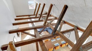 A room with exposed wooden beams, a small window, and a table with chairs. - 4 Star Holiday Home in Lokken (Lokken)
