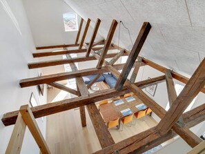 A room with exposed wooden beams, a small window, and a table with chairs. - 4 Star Holiday Home in Lokken (Lokken)