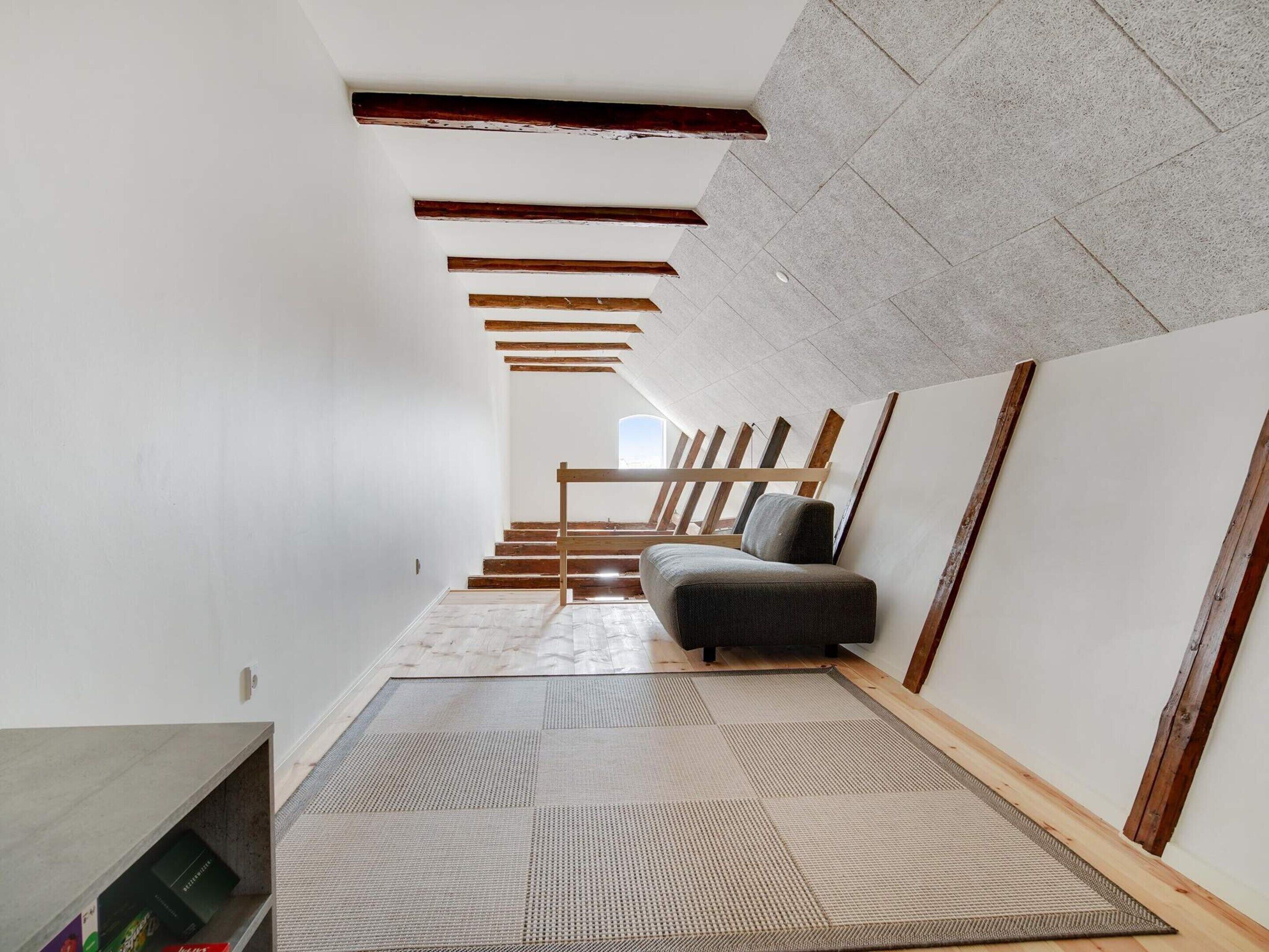 A modern interior with a staircase, a sofa, and a bookshelf.