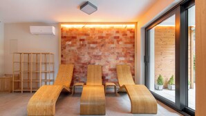 A modern room with three wooden loungers, a wooden wall, a built-in shelf, and a large window.
