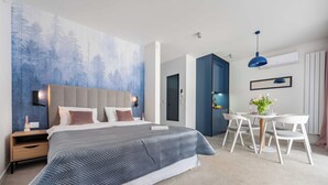 A modern bedroom with a large bed, bedside tables, a desk, and a chair.