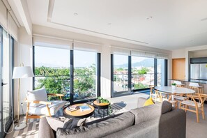 Ein modernes Wohnzimmer mit großen Fenstern, einem Essbereich und einer Küche.