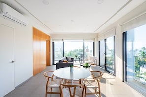 Ein modernes Wohnzimmer mit rundem Tisch und Stühlen, einer Couch und einem Balkon mit Blick.