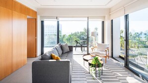 A modern living room with a grey sofa, a wooden wardrobe, a dining area with a table and chairs, and large windows with a city view. - 402 (Puerto Vallarta)