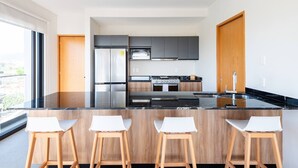 A modern kitchen with a central island, bar stools, a stove, and a refrigerator. - 402 (Puerto Vallarta)