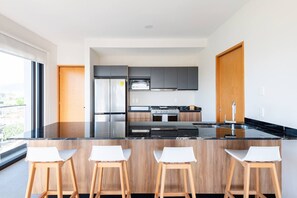 Eine moderne Küche mit Kochinsel, Barhocker, Herd und Kühlschrank.