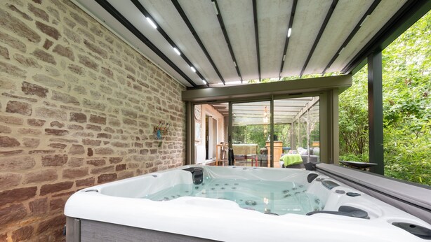 Ein Whirlpool mit Steinwand und Glastür zum Terrassenbereich.