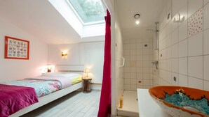 Ein Schlafzimmer mit Oberlicht, Dusche und einem Badezimmer mit einer verzierten Waschette.