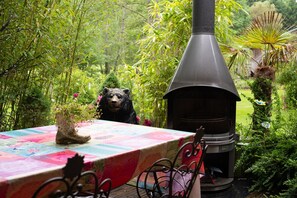 Un jardin avec une table, une statue dâours et un poĂȘle Ă bois.