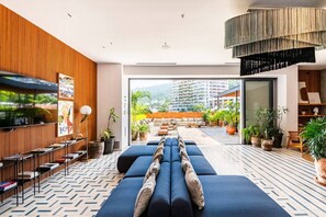 Eine moderne Hotelhalle mit einer langen Couch, einem Fernseher und Blick auf die Stadt.
