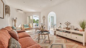 A spacious living room with a large sofa, a coffee table, and a white console table with decorative items. - Holiday Home “Villa Sol Del Este, Es Castell” with Sea View, Wi-Fi and Air Conditioning (Sol del Este)