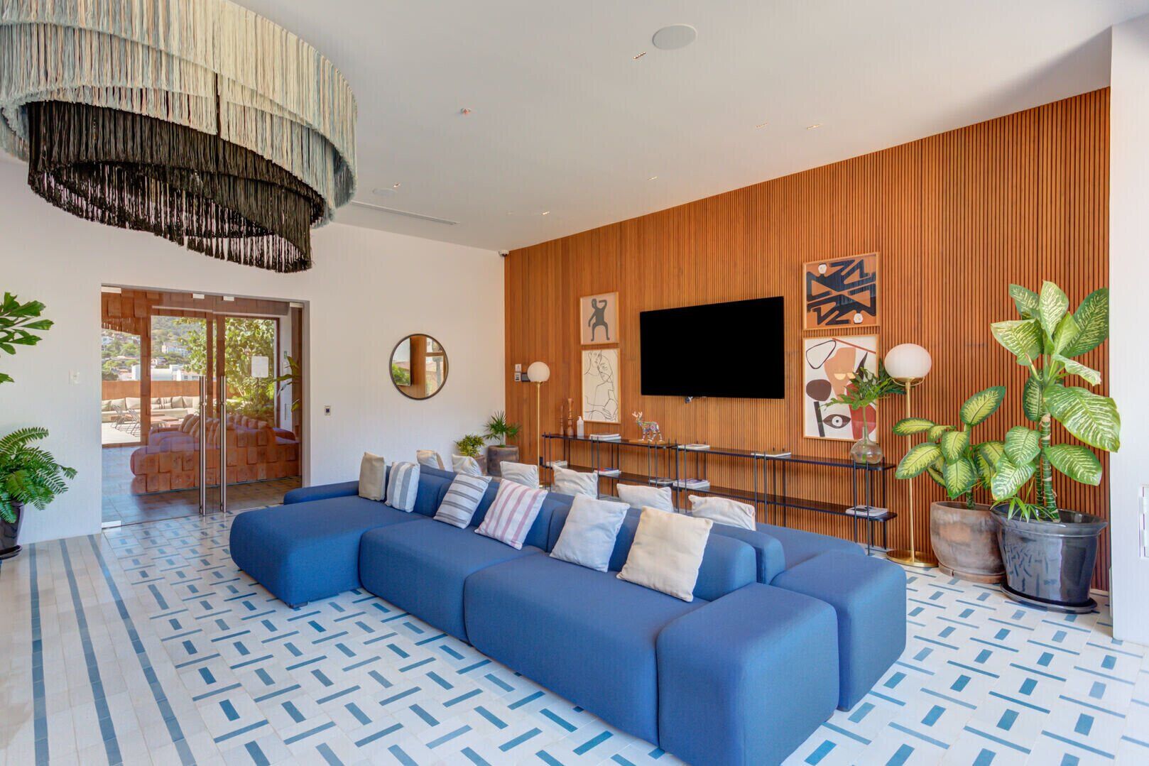 Ein modernes Wohnzimmer mit einem blauen Ecksofa, einem großen Fernseher und einer Holzwand.