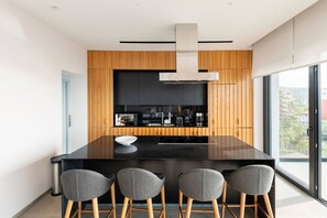 Eine moderne Küche mit einer schwarzen Kücheninsel, Holzvertäfelung und einem großen Fenster.