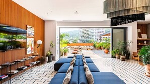 Een moderne hotellobby met een lange bank, een televisie en uitzicht op de stad.