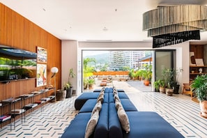 Eine moderne Hotelhalle mit einer langen Couch, einem Fernseher und Blick auf die Stadt.