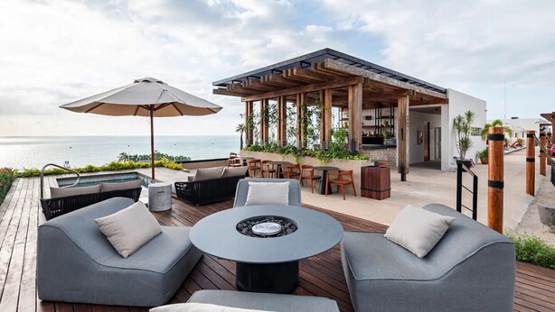 Een terras met buitenmeubilair, een vuurkorf en uitzicht op de oceaan.