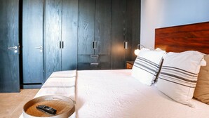 Een slaapkamer met een bed, kussens, een afstandsbediening en een kledingkast.