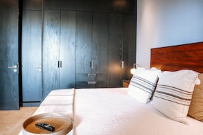 Ein Schlafzimmer mit einem Bett, Kissen, einer Fernbedienung und einem Kleiderschrank.